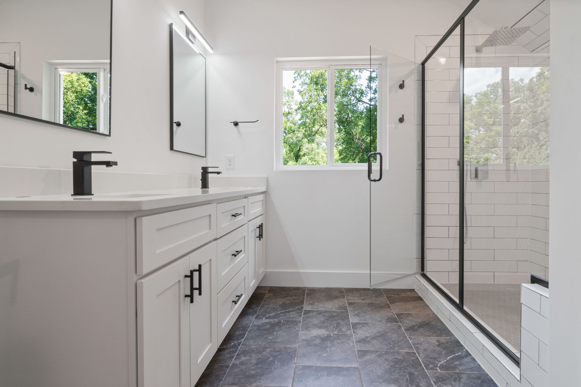 Elegant, sunlit bathroom featuring a glass-enclosed shower and sleek black fixtures for a modern touch.