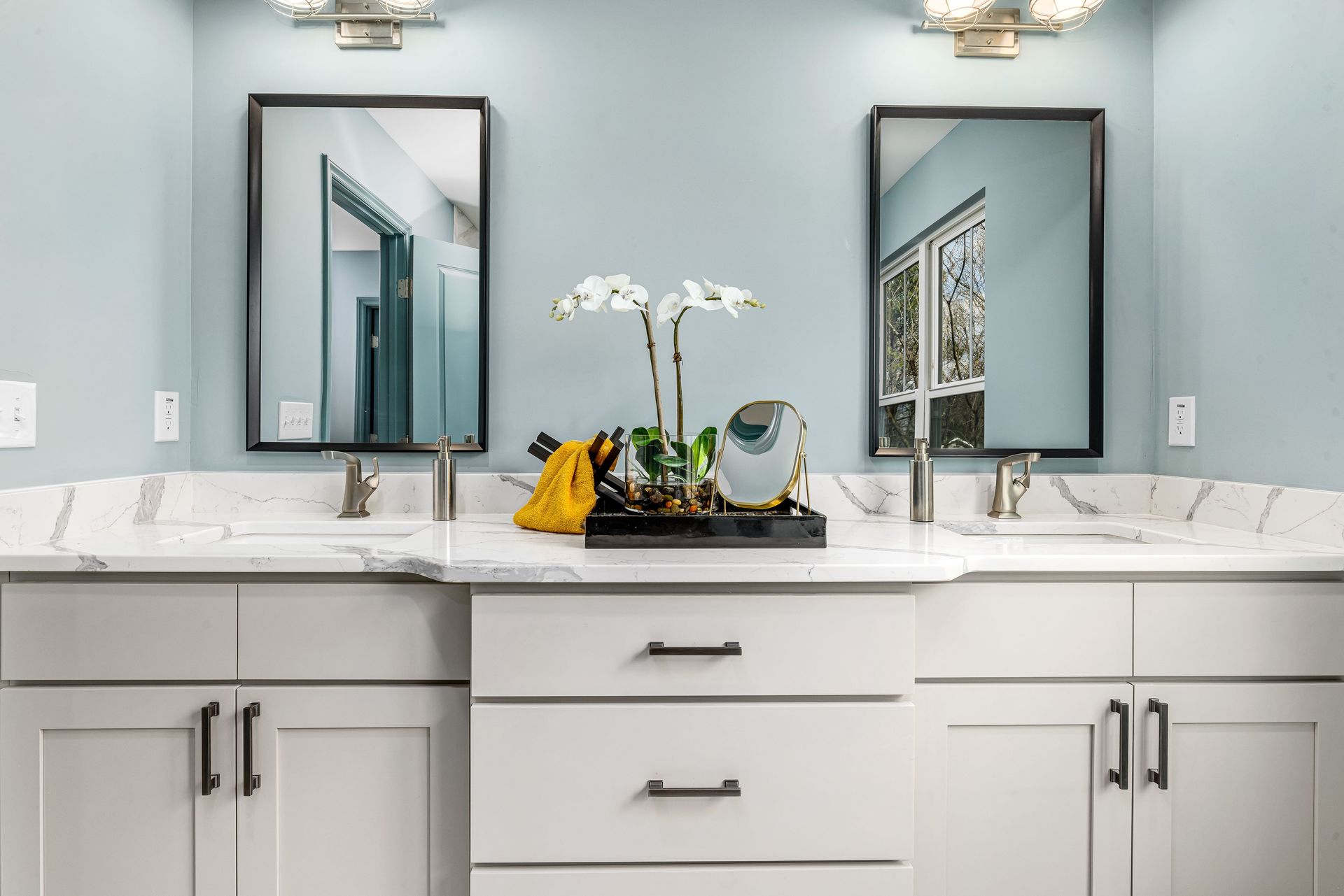 A serene modern bathroom featuring twin sinks, elegant faucets, and decorative mirrors.